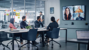 Businesspeople do Video Conference Call with Big Wall TV in Office Meeting Room